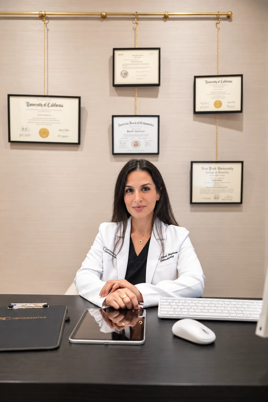 Dr. Shadi Haykani at her consultation desk, with her board certification and diplomas behind her