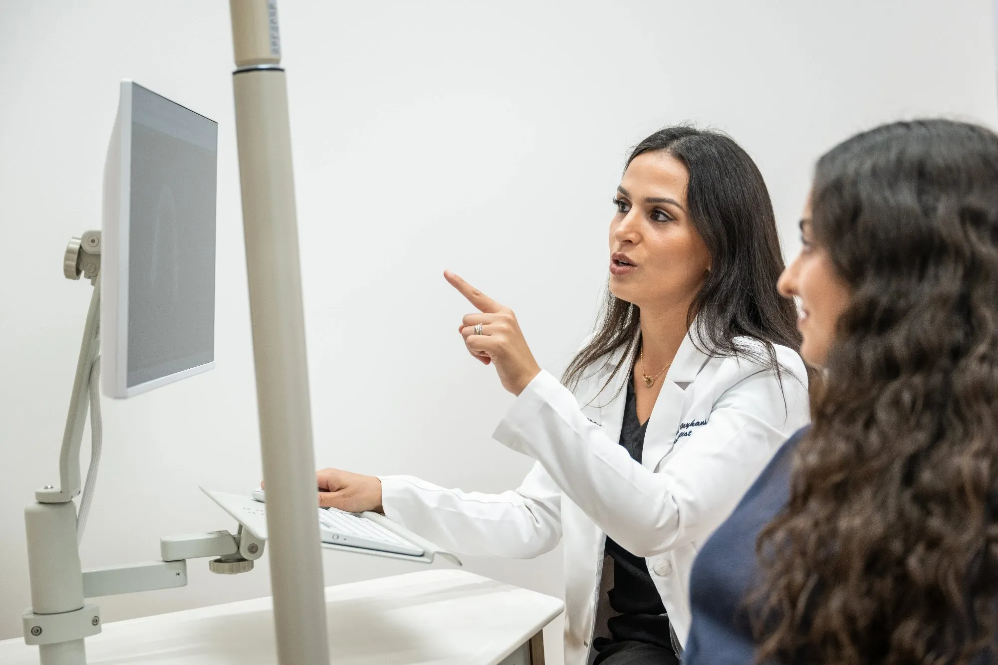 Dr. Haykani discussing records on a monitor with an adult patient.