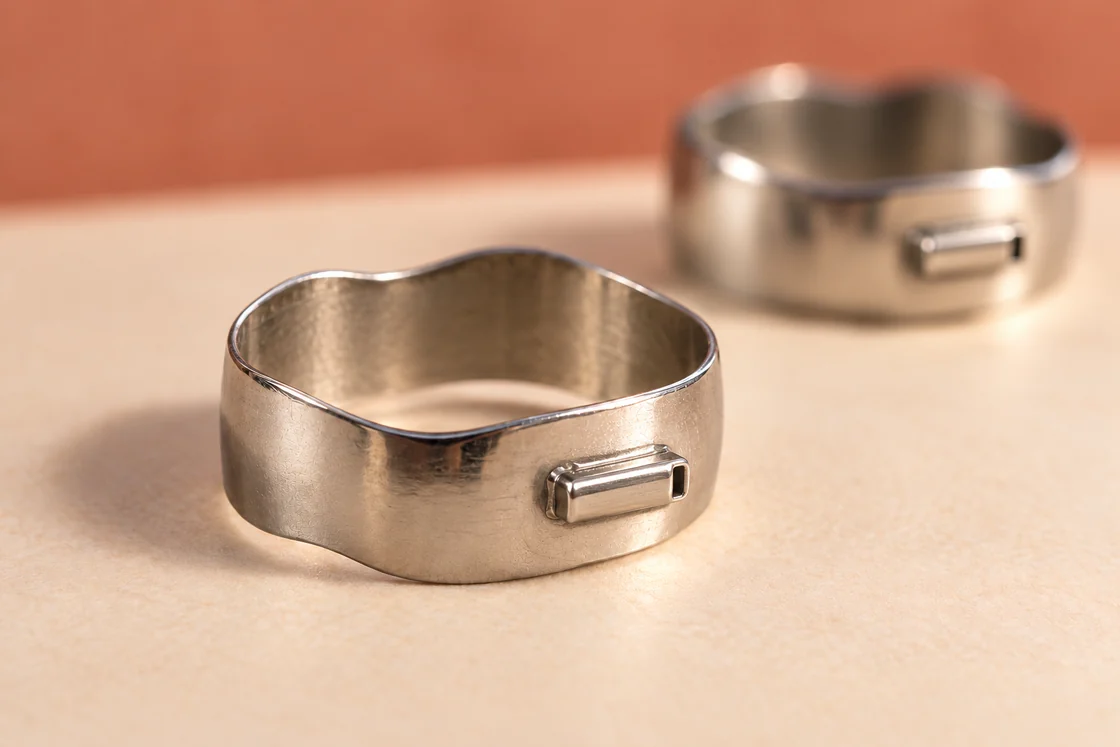 Two open stainless-steel orthodontic bands on an ivory surface.