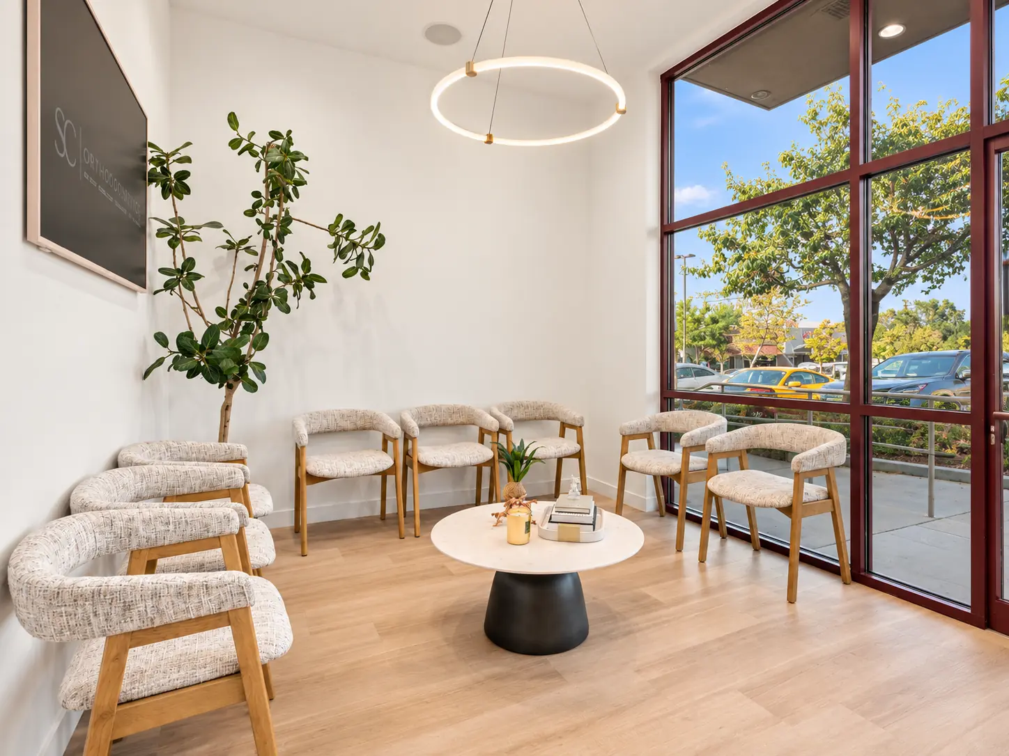 The patient lounge at SC Orthodontics in Valencia, with window light and a round pendant