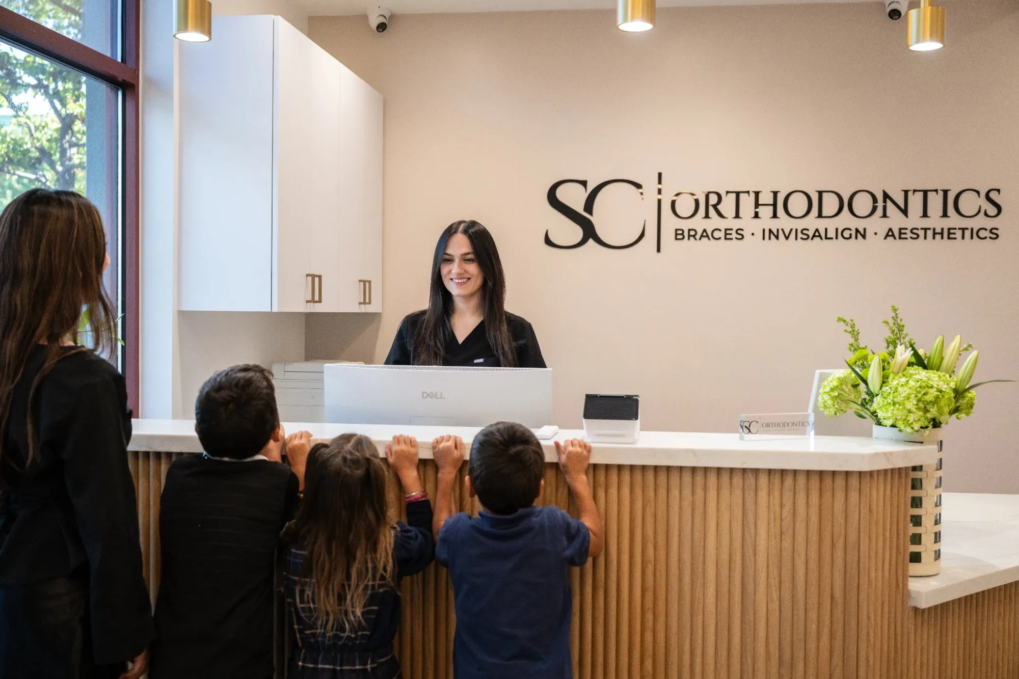 A family checking in at the SC Orthodontics front desk in Valencia, where insurance is verified before the first visit