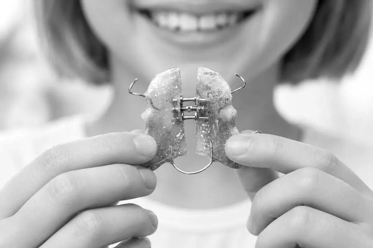 A young patient holding a palatal expander appliance